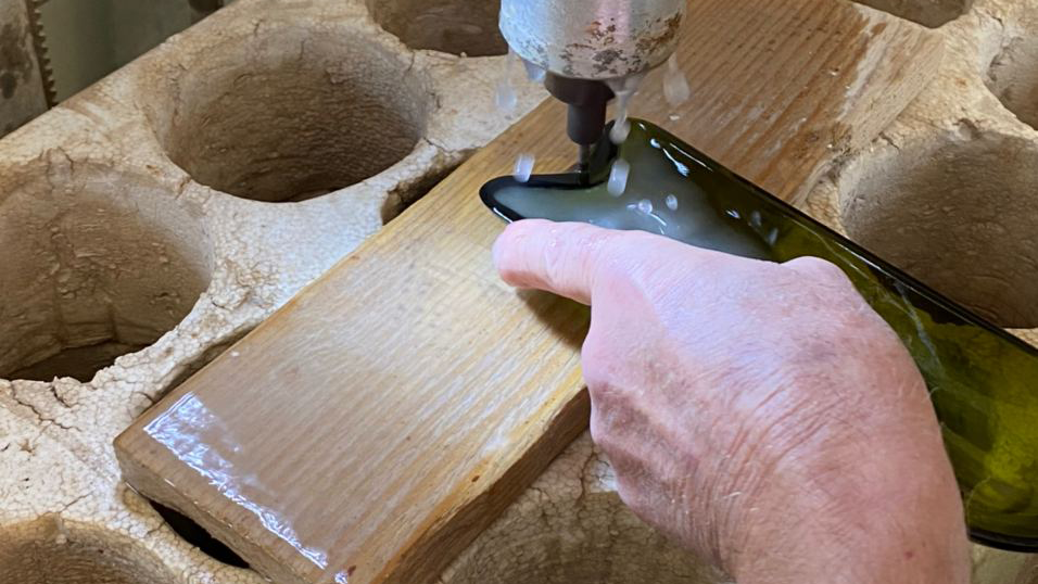 Lavorazione artigianale di una bottiglia di vetro verde.